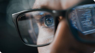 A user with code reflecting in their eyeglasses