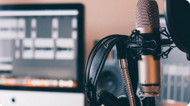 Microphone with headphones hanging on it, used on podcasts