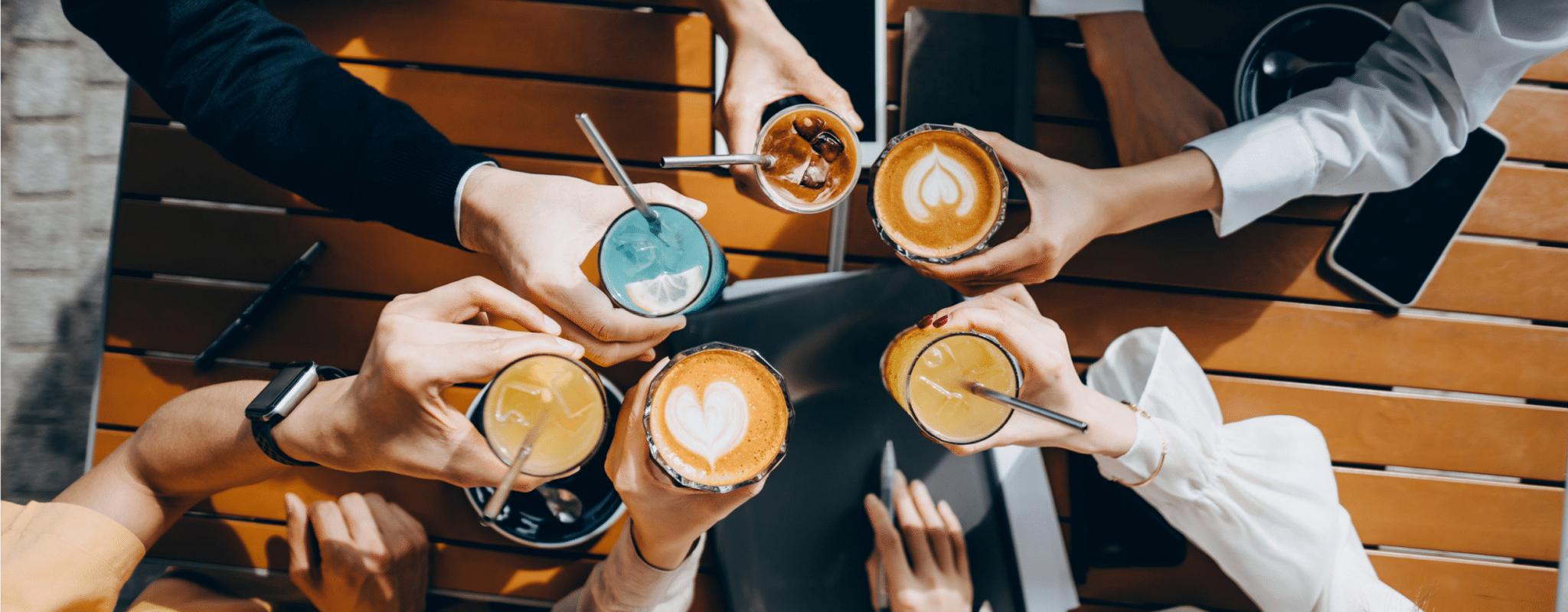 A group of people place their various drinks of different colors in the center to cheers.