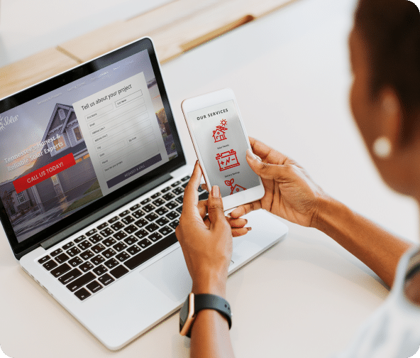 A lady with a mobile phone in hand with Swaggerty's custom app opened and a laptop on the table with Swaggerty's website.