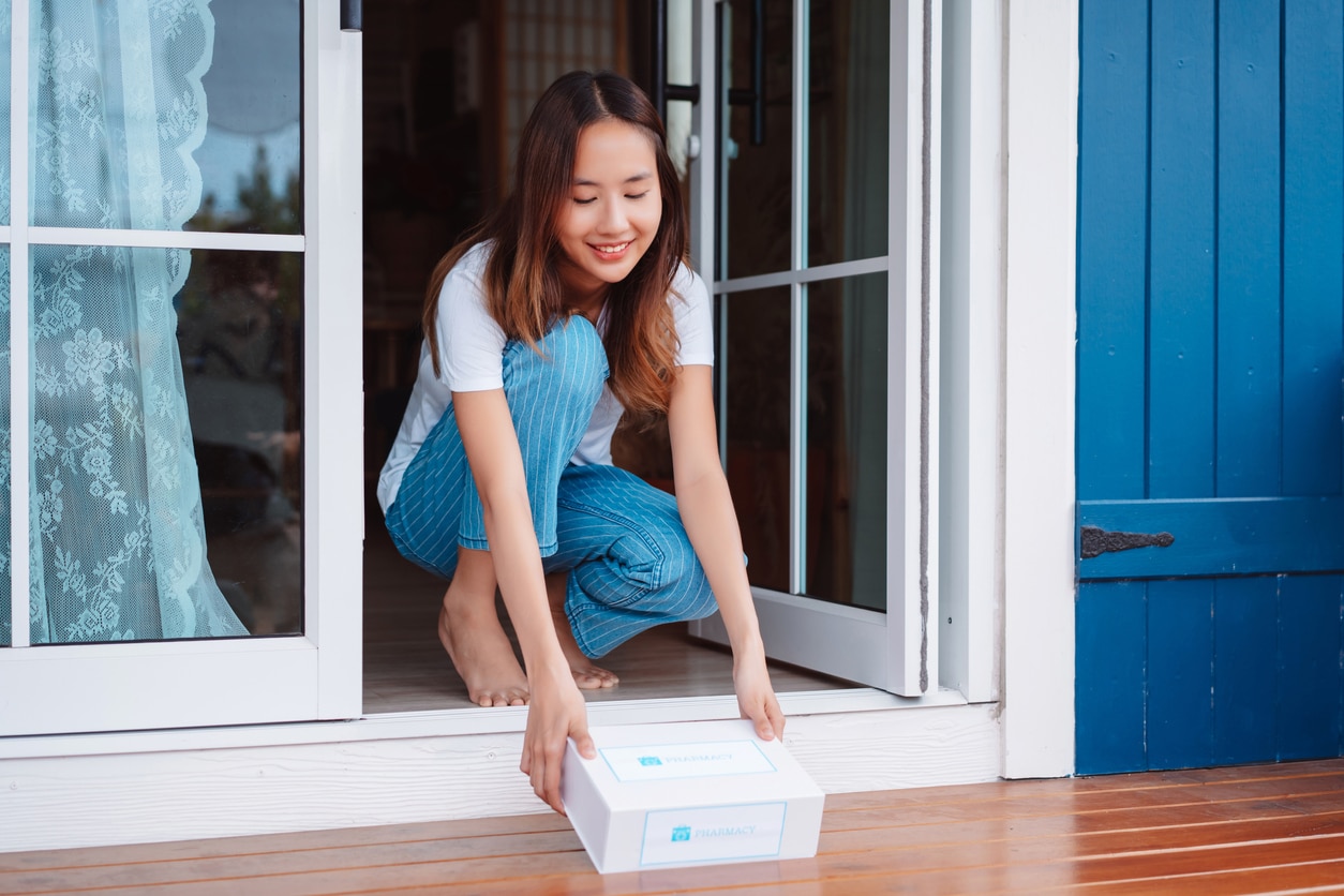 Woman patient grabs COVID test from front door. Customer delivery service from hospital online clinic.