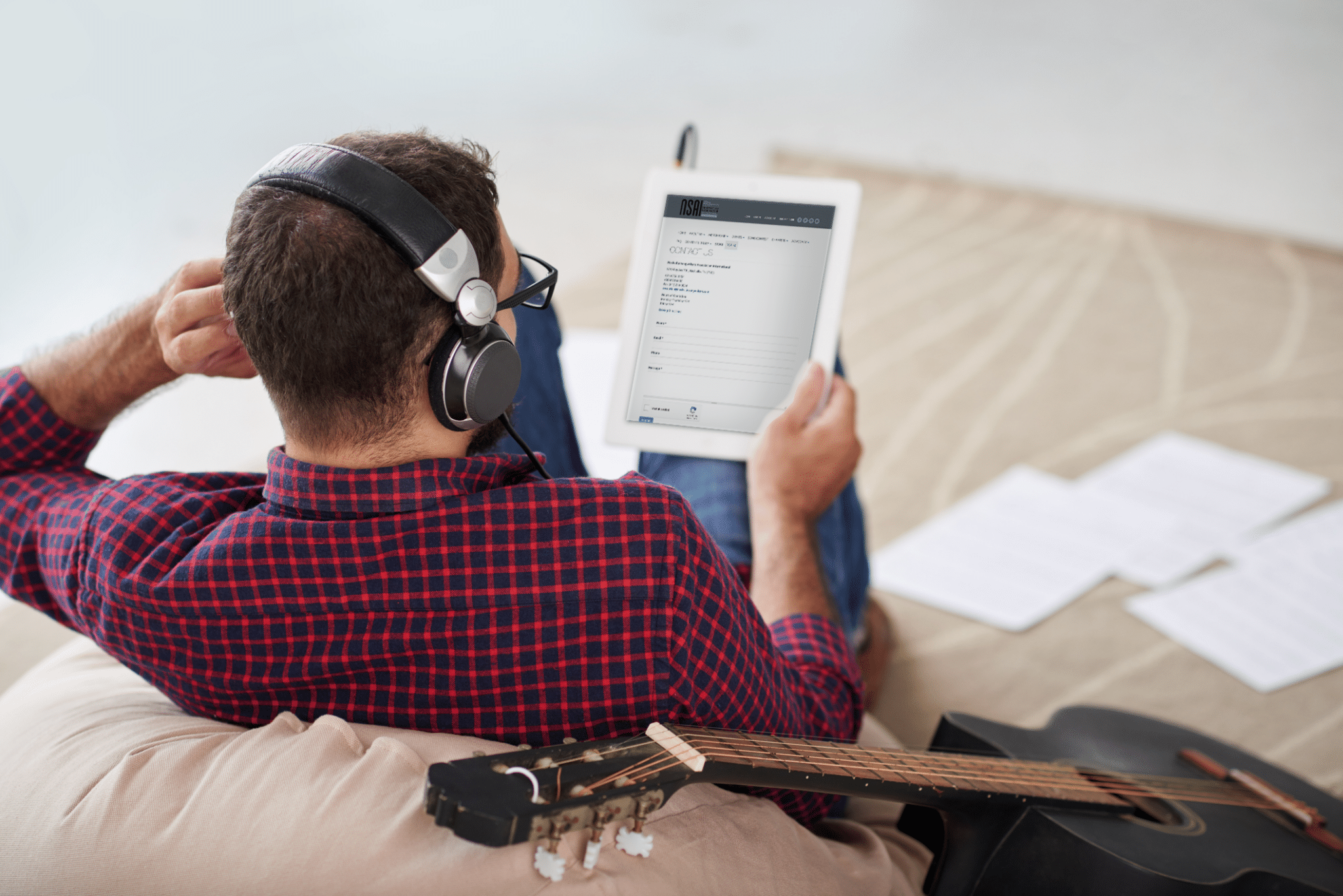 Person sits with headphones, holding a laptop filling out the Contact form on the NSAI website.