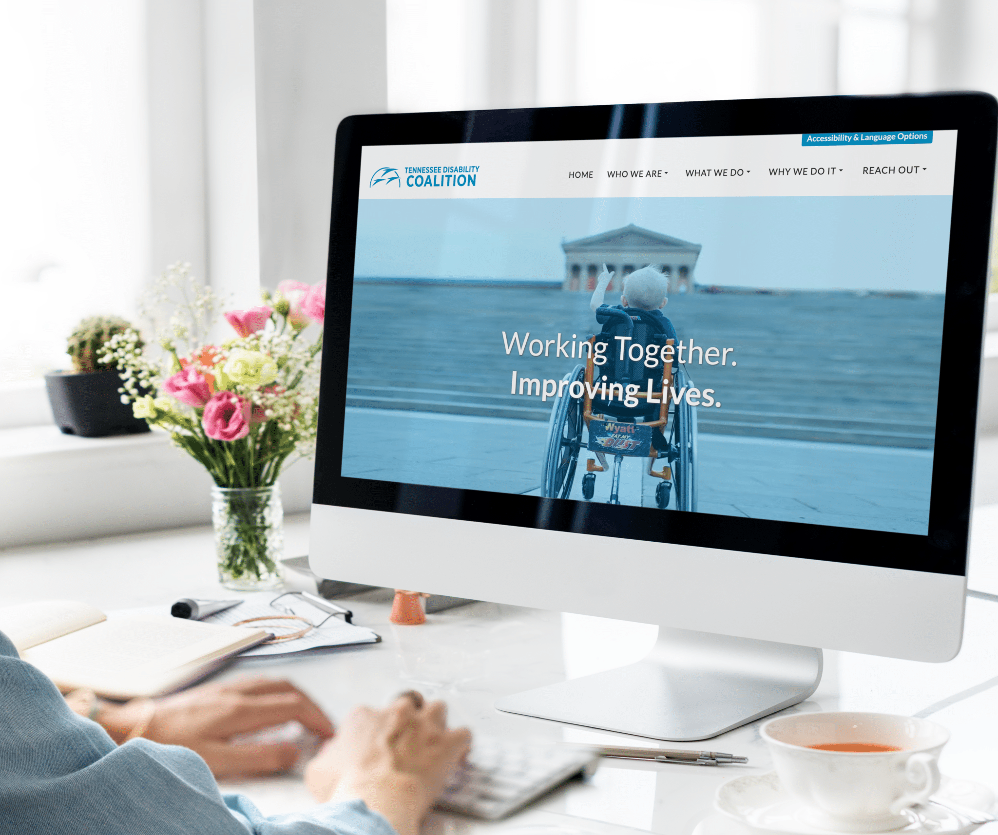 Monitor sits on a desk with the TNDIS homepage showing as person scrolls through website.