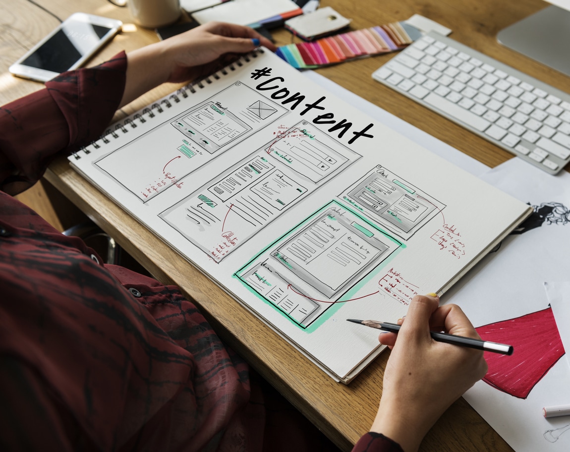 Person sits at desk with TNDIS content designs drawn out for new website.