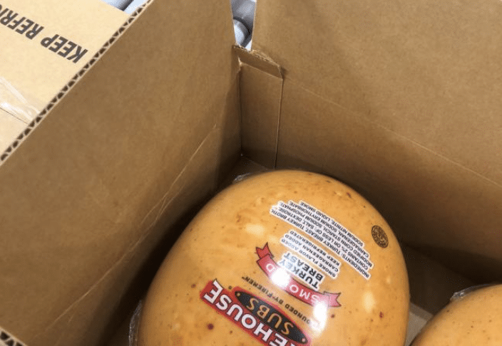An open box with smoked turkey breast packed inside.