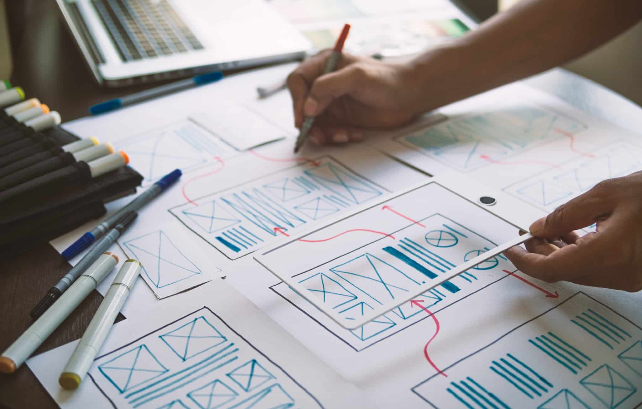 Person making edits to app development layout with design and diagram examples.