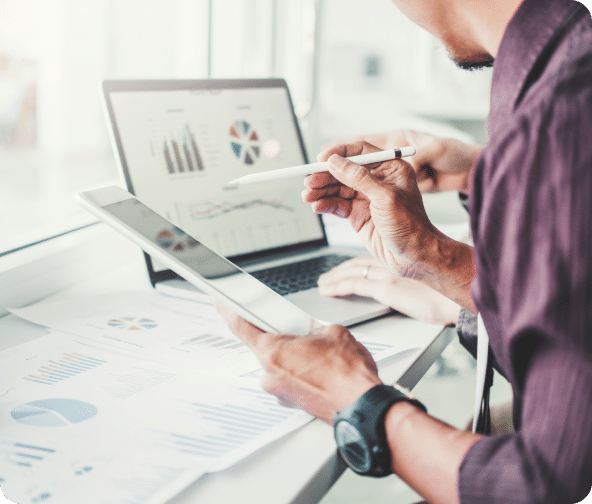 Person uses a laptop and tablet to review data insights.