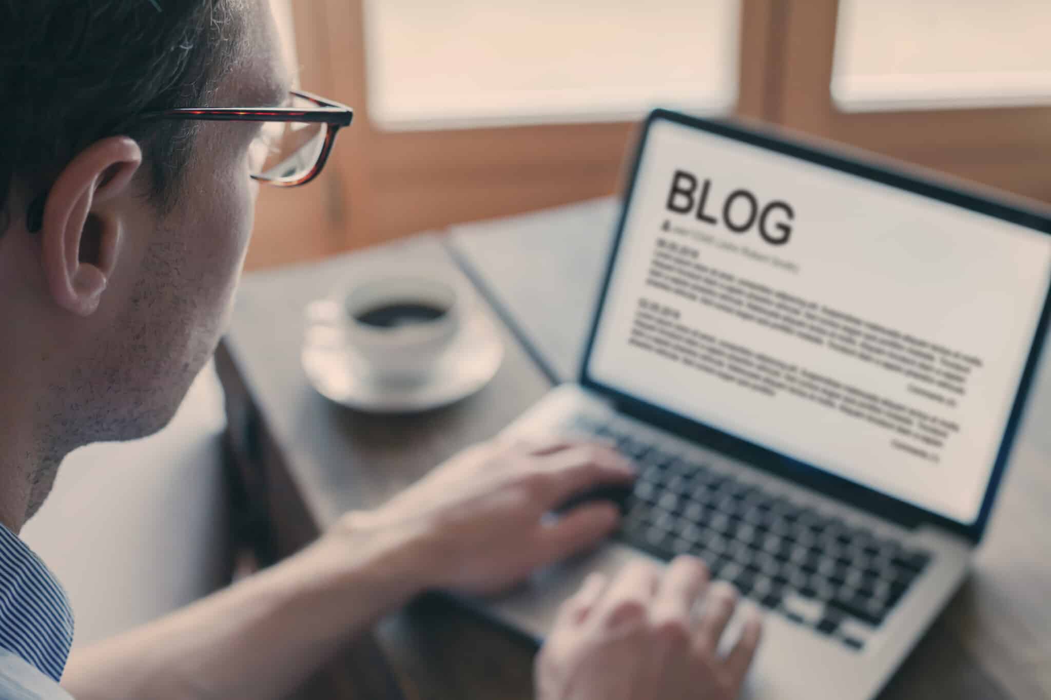 Person sits at laptop creating blog content for website.
