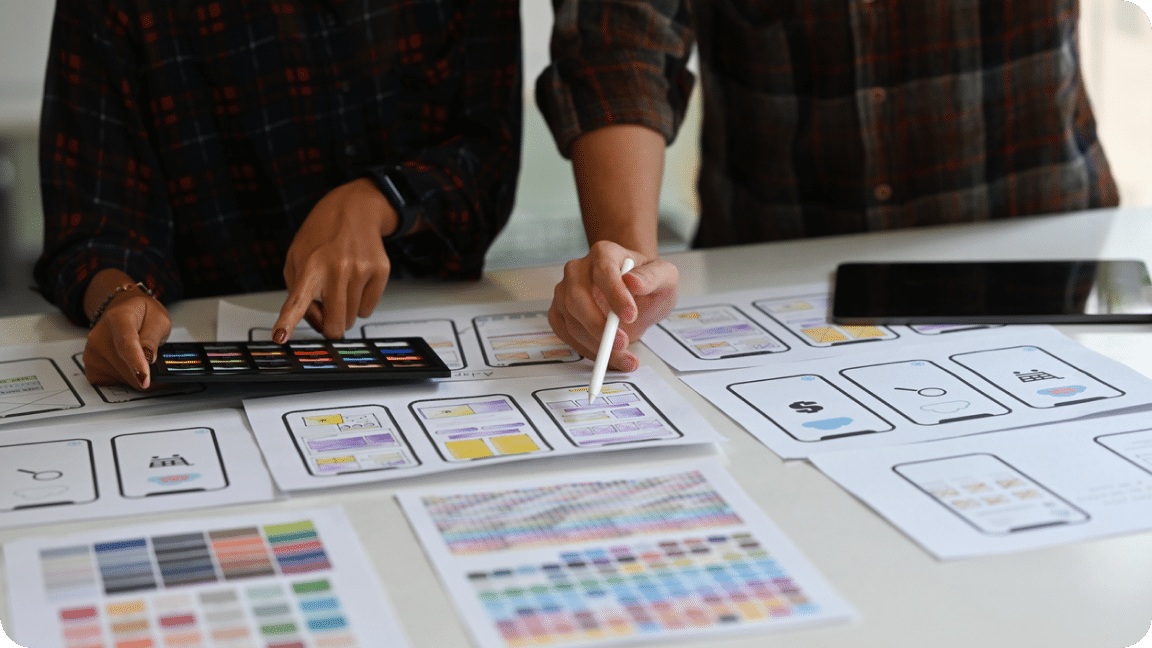 A team reviews strategy laid out in hardcopy assets and digital with ipads.