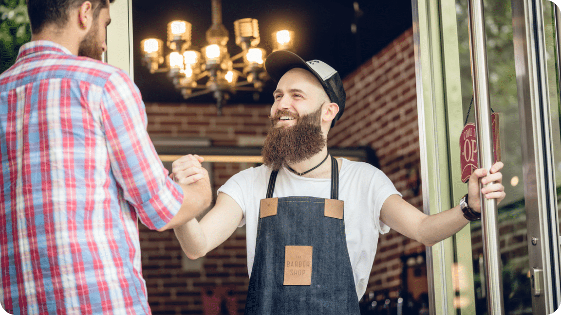 Two people shake hands and smile at each other.