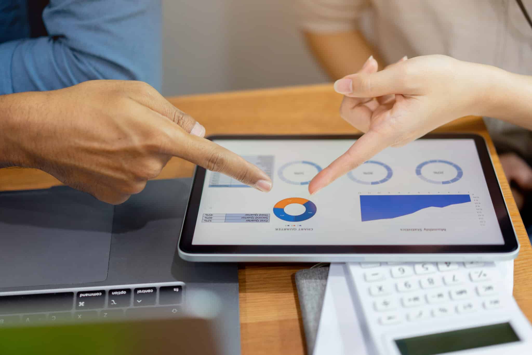 Two fingers point to a circle graph on a tablet with other metrics visible.