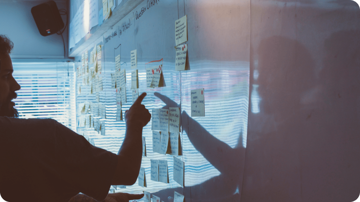 Whiteboard with sticky notes and a person reviewing the strategy notes.