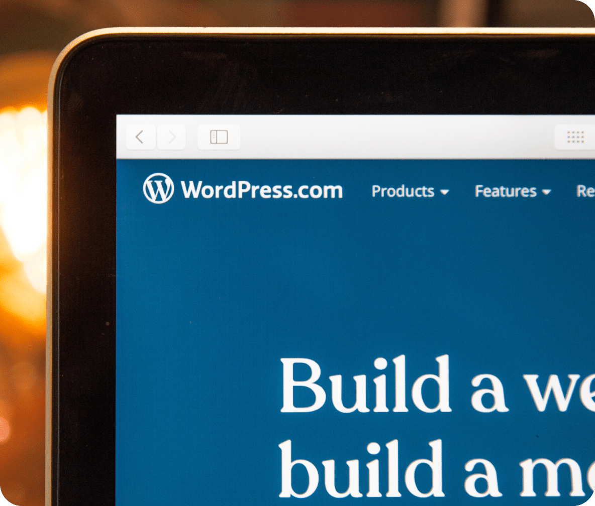 Corner of a laptop showing the WordPress logo and part of the homepage.