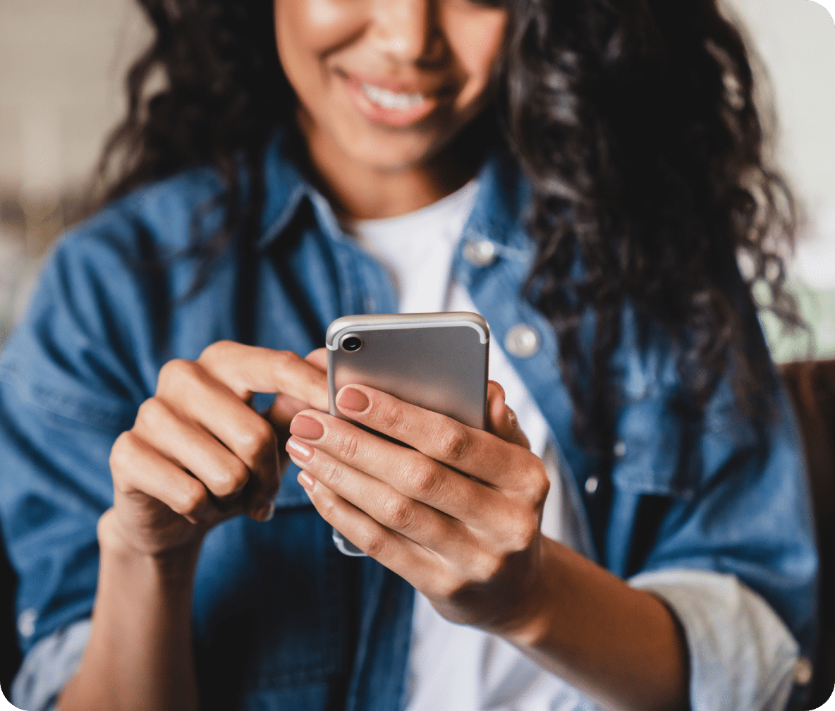 Smiling down at their mobile phone, a user scrolls through a website.