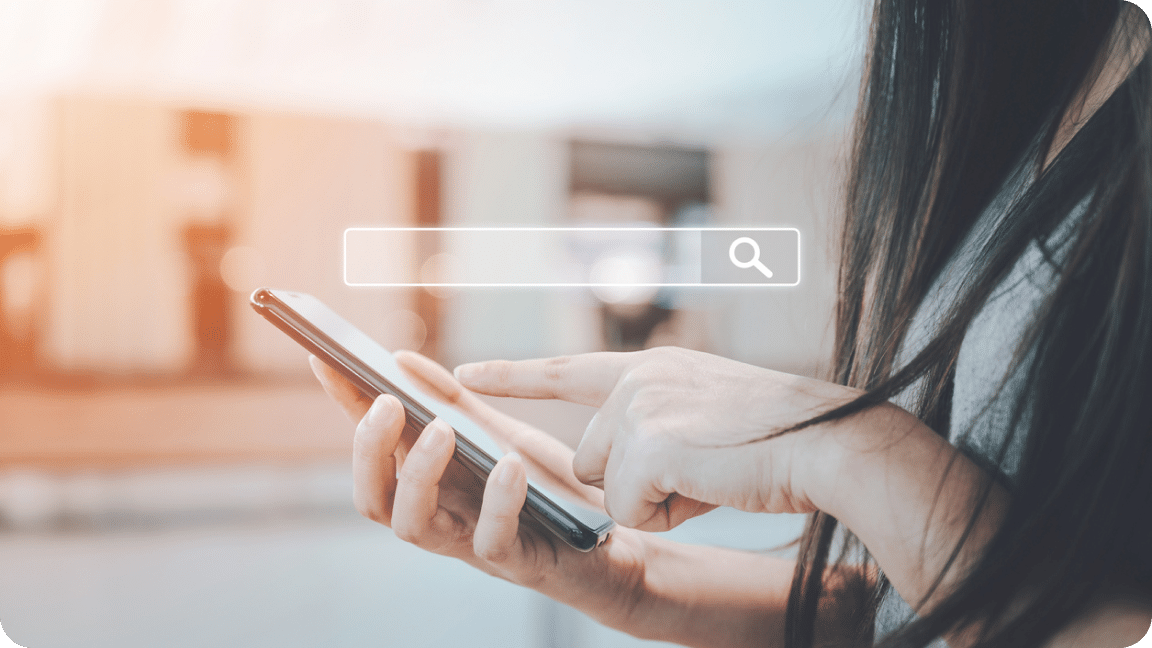 One hand holds a cellphone while the other hand scrolls the screen, with a search bar icon overlay.