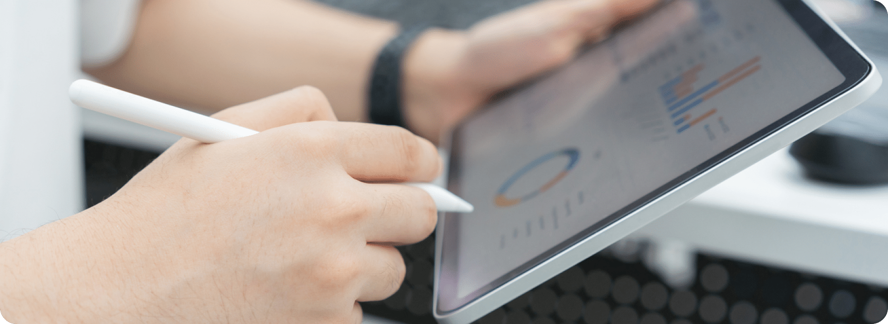 One hand holds a stylus with the other hand holding a tablet as they review website metrics.