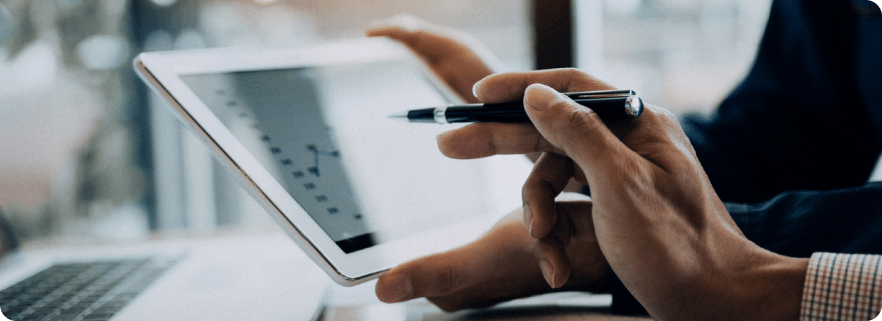 One person holds an iPad while the other points to data on the screen.
