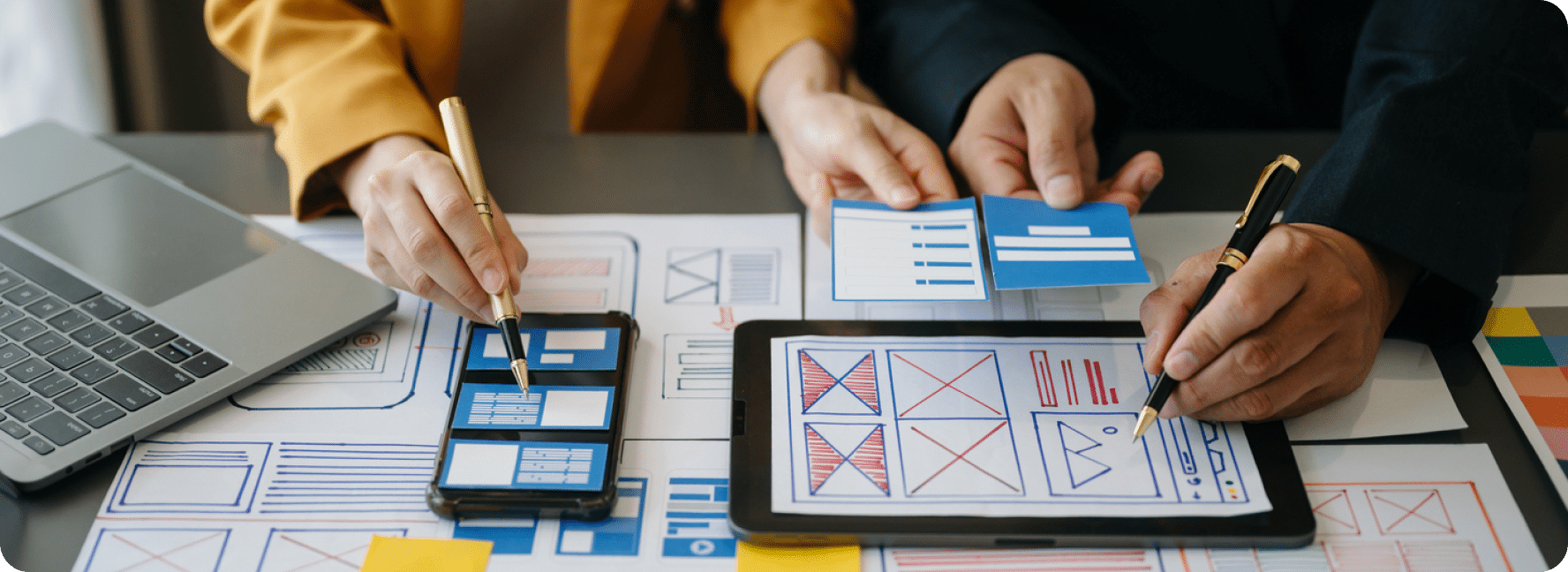 A mobile phone and tablet lay on a table with other designs and layout drawings.