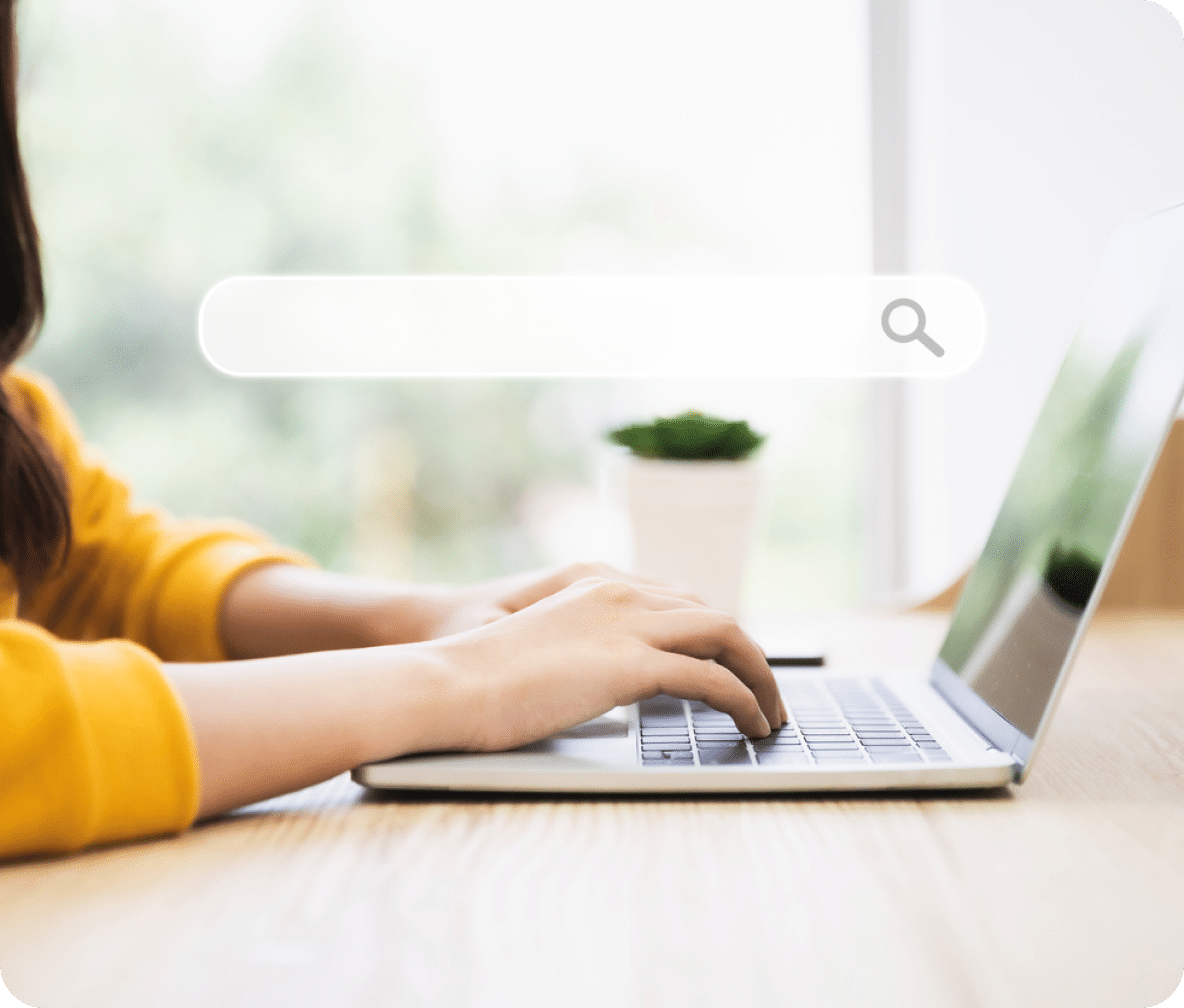 Search bar with search icon at the top with an open laptop and hands on the keyboard.