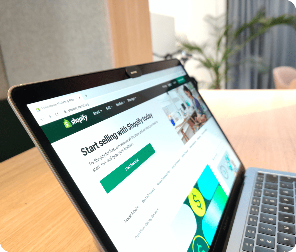 Laptop screen displays the Shopify home page.