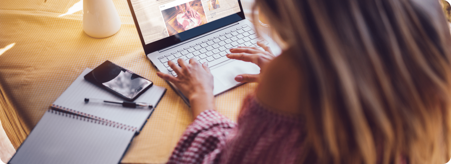 Experienced content writer types on their laptop with their notebook open to the side.