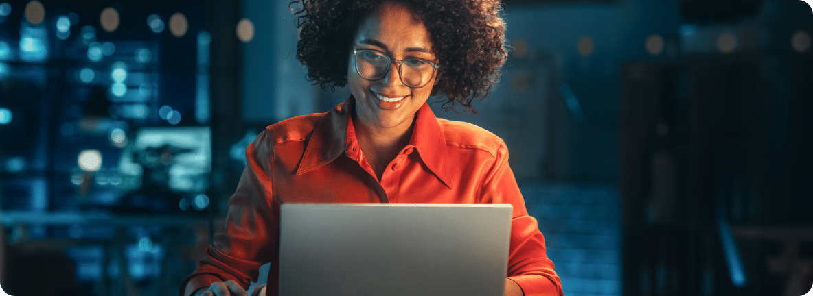 Smiling at an open laptop, the person sitting, smiles as they review their business suite of website tools.