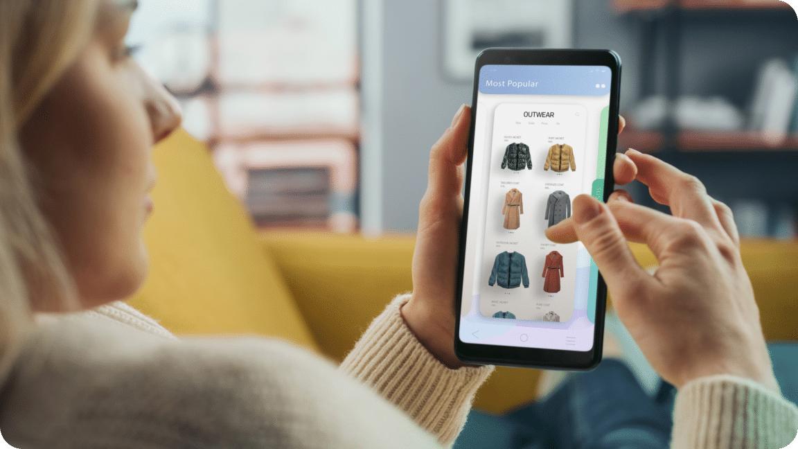 Person sits with their cellphone in hand, scrolling through jackets as the shop online.