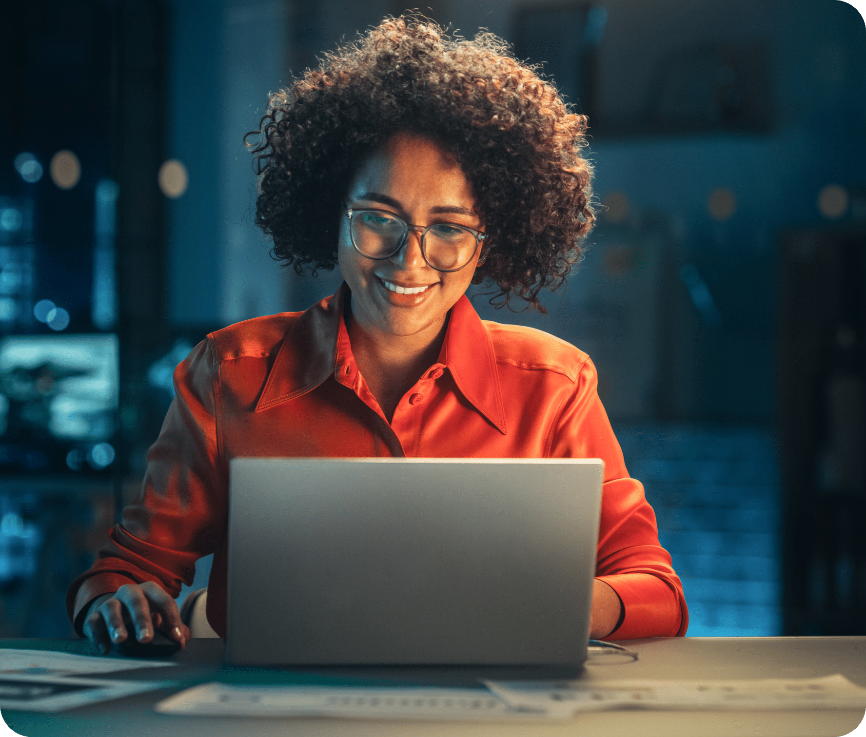 Sitting at a desk, in front of an open laptop, business owner smiles down.