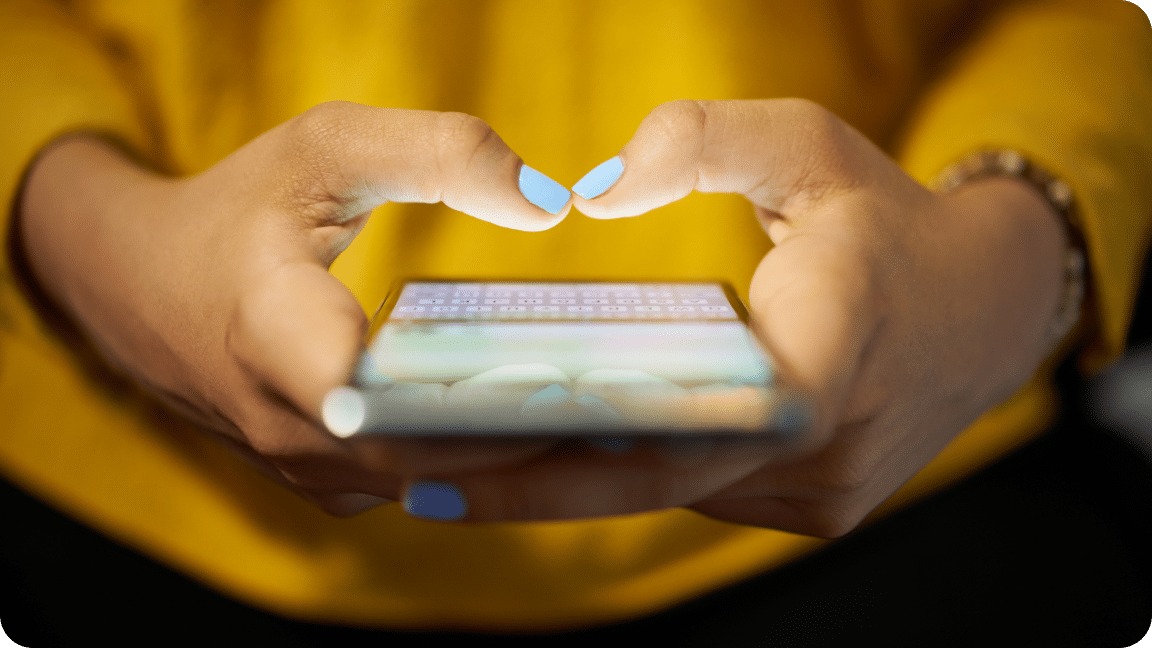 Two hand hold a cellphone with the keyboard activated as they type on the screen.