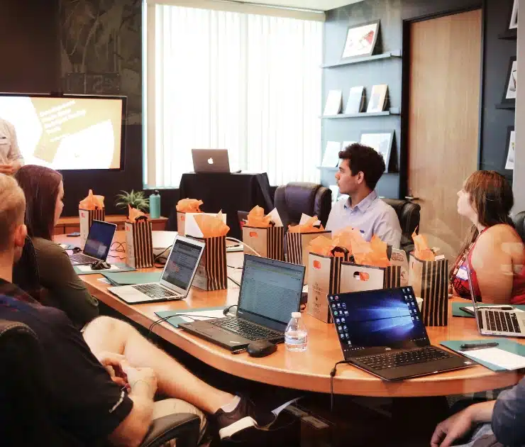 Marketing strategy discussion in a room with a long table, dark brown leather chairs, with people seated, looking at a presentation.