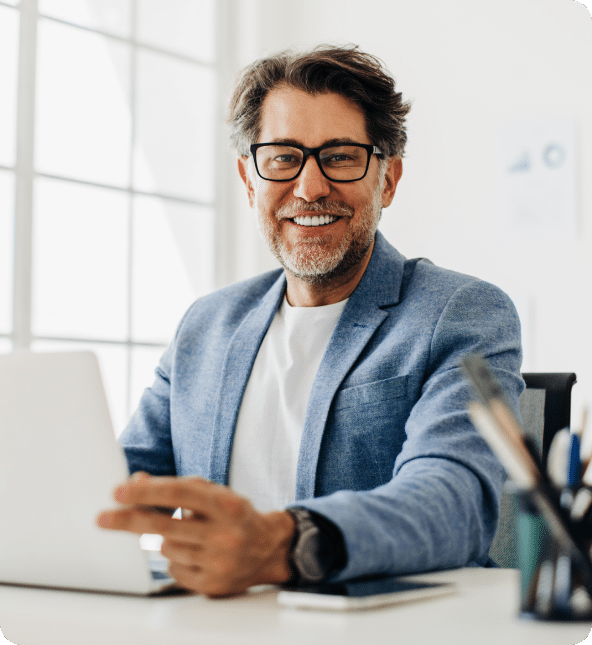 A man in a blue blazer and laptop in hand, smiling at the camera showing joy after getting Turnkey website services.